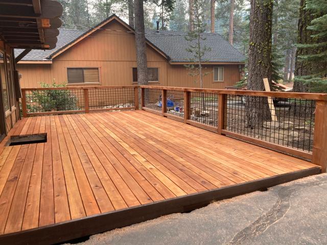 New cedar deck with hog wire railing framed by tall Tahoe pines