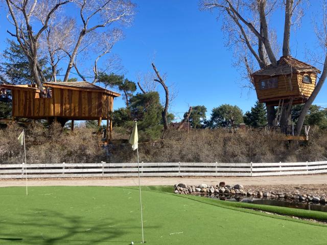 Two custom wooden treehouses overlooking a putting green and pond