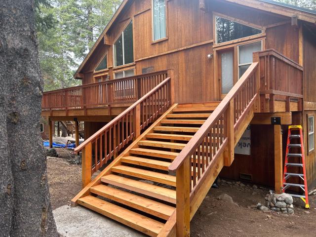 New redwood staircase and wraparound deck railings on a Tahoe cabin among pines
