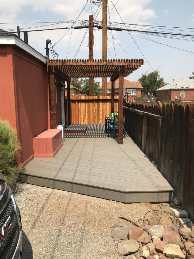 Gray composite deck with stained wood pergola along a fenced side yard