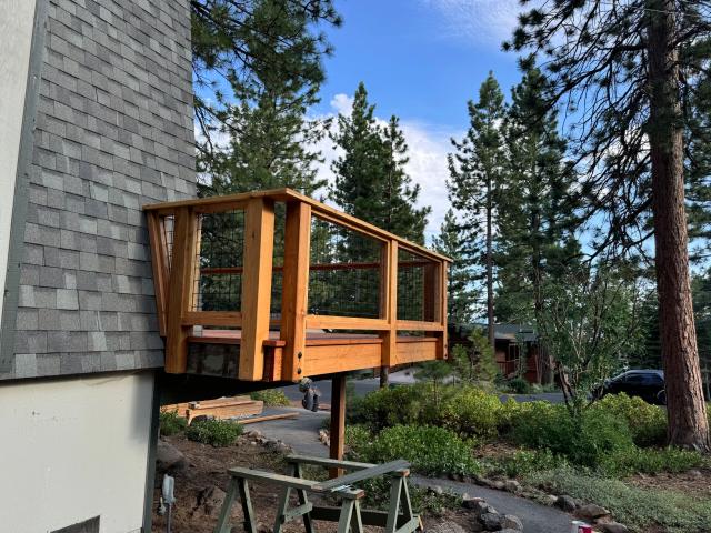 Elevated cedar balcony with hog-wire railing panels on a shingle-sided home